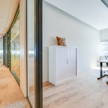 Moderne kantoorruimte met glazen wanden en houten vloer aan De Entree 99-197 in Amsterdam Zuid-Oost, ingericht met bureau en kast, beschikbaar voor kantoorruimte huren.