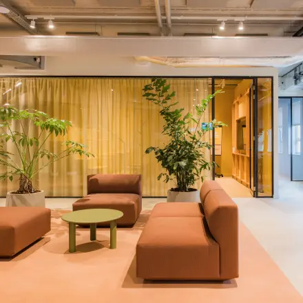 Moderne kantoorruimte in Amsterdam Zuid-Oost met stijlvolle zitbanken en groene planten, ideaal om te huren voor creatieve brainstormsessies.