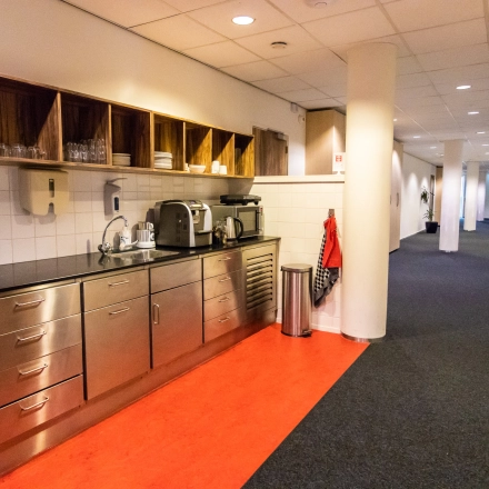 Koffiepauzehoek in kantoorpand op Hullenbergweg 278, met roestvrijstalen aanrecht en open houten schappen, gelegen in Amsterdam Zuid-Oost.