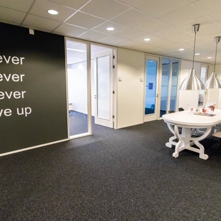 Kantoorruimte op Hullenbergweg 278, Amsterdam Zuid-Oost met een inspirerende muurtekst, moderne inrichting en vergadertafel. Ideale locatie voor kantoorruimte huren.