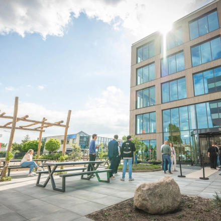 Moderne kantooromgeving aan de Luttenbergweg 8, Amsterdam Zuid-Oost, met mensen die zakelijk overleggen bij picknicktafels buitenshuis voor een ruim en uitnodigend kantoorpand.