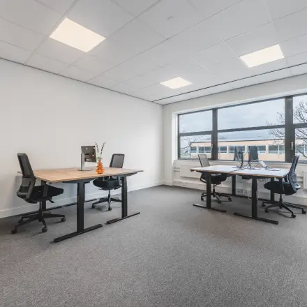 Modern ingerichte kantoorruimte op Paasheuvelweg 20 in Amsterdam Zuid-Oost met vier bureaus en comfortabele stoelen bij grote ramen.