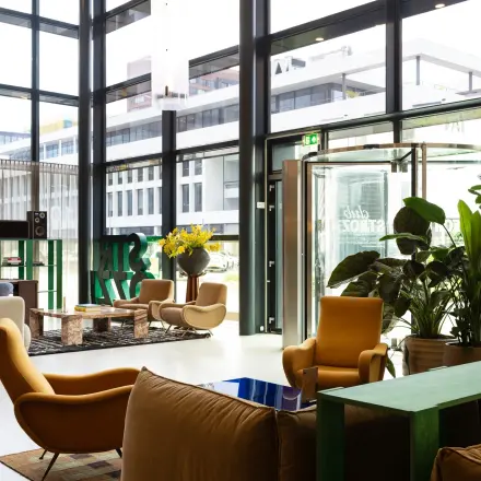 Moderne werkruimte in kantoorpand op Barbara Strozzilaan 101, Amsterdam Zuidas, met comfortabele zitplekken, veel groen en grote ramen voor natuurlijk licht.
