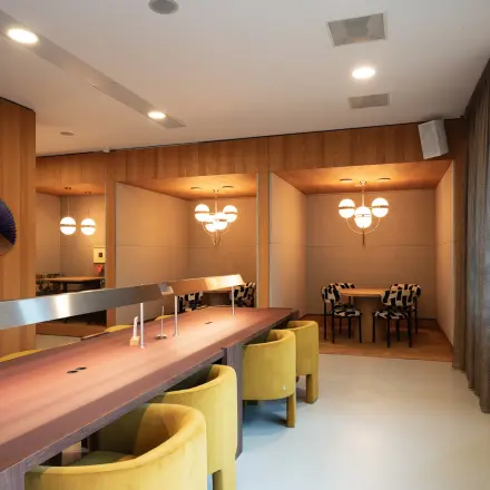 Moderne kantoorruimte met houten tafel en gele stoelen op Barbara Strozzilaan 101, Amsterdam Zuidas, geschikt voor werk of vergaderingen. Verfijnd interieur met decoratieve elementen en sfeerverlichting.