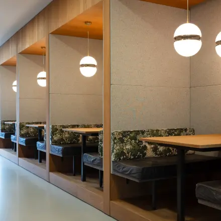 Stijlvolle werkplekken in het kantoorpand aan de Barbara Strozzilaan 101 in Amsterdam Zuidas. Houten nissen met tafels onder moderne hanglampen bieden een inspirerende ruimte voor kantoorruimte huren.