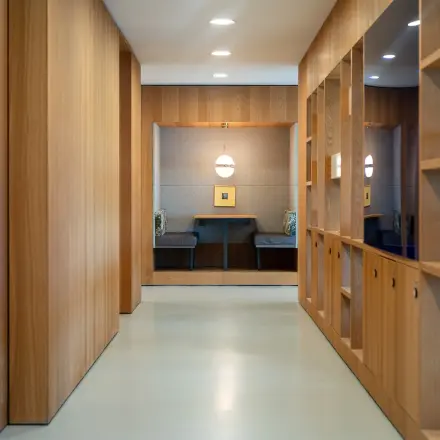 Moderne kantoorgang met strakke houten panelen en ingebouwde kasten, gelegen aan de Barbara Strozzilaan 101 in Amsterdam Zuidas. Geschikt voor kantoorruimte huren.