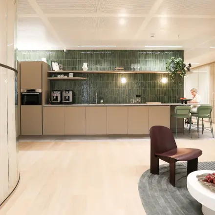 Kantoorruimte huren op Beethovenstraat 503, Amsterdam Zuidas, met gemeubileerd interieur, waaronder een zithoek en pantry waar iemand aan het werk is aan een tafel.