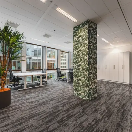 Moderne kantoorruimte te huur op Claude Debussylaan 10, Amsterdam Zuidas. Ruimte met glazen wanden, planten en bureaus, ideaal voor zakelijk gebruik. Geschikt voor kantoorgebruik met brede werkplekken.