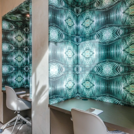 Moderne kantoorruimte te huur in Amsterdam Zuidas met stijlvolle wandbekleding en comfortabele bureaustoelen, ideaal voor productief werken.