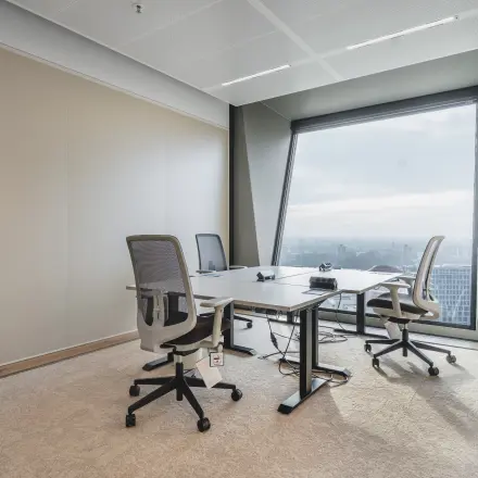 Kantoorruimte huren in Amsterdam Zuidas met uitzicht over de stad, voorzien van moderne bureaus en comfortabele stoelen, ideaal voor productieve werkuren.