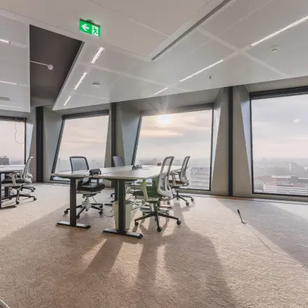 Kantoorruimte te huur aan Hildegard Von Bingenstraat 44 in Amsterdam Zuidas, met grote ramen en uitzicht over de stad. Het kantoorpand biedt moderne werkplekken met tafels en bureaustoelen.