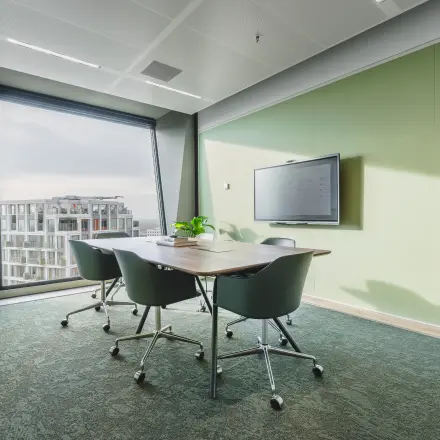Moderne vergaderruimte in kantoorpand op Hildegard Von Bingenstraat 44, Amsterdam Zuidas, met groene muren, een grote tafel en comfortabele stoelen. Geschikt voor kantoorruimte huren.