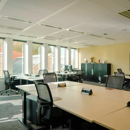 Kantoorruimte huren aan de Jachthavenweg 109 in Amsterdam Zuidas, met een open indeling, bureaus en stoelen, veel natuurlijk licht en wanddecoraties.