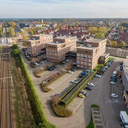 Luchtfoto van het kantoorpand aan Het Rietveld 55-59 in Apeldoorn, omgeven door parkeerplaatsen en nabij het spoor. Ideaal voor wie een kantoorruimte wil huren.
