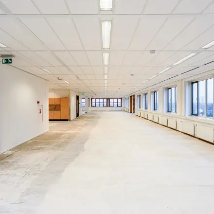 Grote, lichte kantoorruimte in kantoorpand aan Het Rietveld 55-59, Apeldoorn, zonder meubilair. Lange ruimte met ramen aan één zijde. Geschikt voor huur als open kantoor.