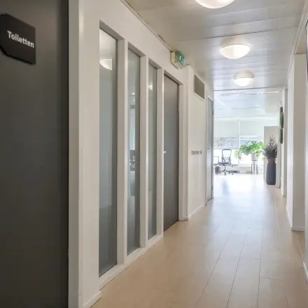 Lichte gang in kantoorpand aan Prins Willem-Alexanderlaan 301 in Apeldoorn, met houten vloer en toegang tot verschillende kantoorruimtes.