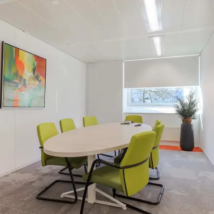 Kantoorruimte huren aan de Prins Willem-Alexanderlaan 301 in Apeldoorn, met een vergadertafel en zes groene stoelen onder helder licht.