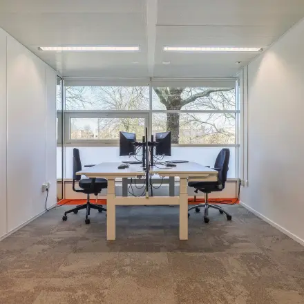 Kantoorruimte huren op Prins Willem-Alexanderlaan 301 in Apeldoorn met twee werkplekken, bureaus en stoelen, en veel natuurlijk licht.