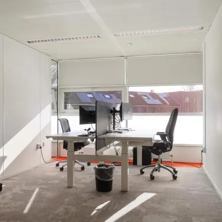 Kantoorruimte huren op Prins Willem-Alexanderlaan 301 in Apeldoorn, met twee bureaus, stoelen en computerschermen. Grote ramen bieden veel daglicht in het kantoorpand.