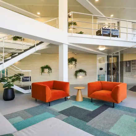 Moderne kantoorruimte te huur aan de Prins Willem-Alexanderlaan 301 in Apeldoorn, met kleurrijke meubels en een open indeling. Het kantoorpand is ingericht met zitgedeeltes en planten voor een frisse werkplek.