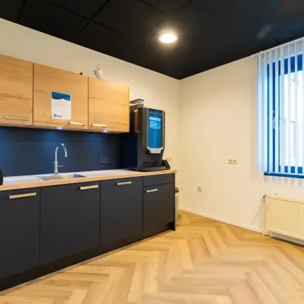Een moderne pantry met houten kasten, een koffiezetapparaat en een spoelbak in een kantoorpand op Prins Willem Alexanderlaan 701, Apeldoorn. Perfect voor wie kantoorruimte wil huren.