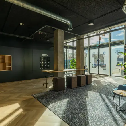 Moderne kantoorlobby op Prins Willem Alexanderlaan 701, Apeldoorn, geschikt om te huren, met een minimalistisch ingericht interieur en natuurlijk licht van grote ramen.