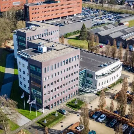 Luchtfoto van een modern kantoorpand op Schumanpark 9, Apeldoorn met meerdere verdiepingen en parkeerplaatsen eromheen.