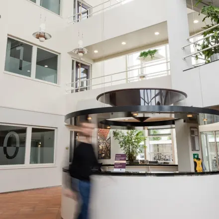 Lichte en ruime entree van een kantoorpand op Vlamoven 34 in Arnhem IJsseloord, met een receptiebalie en moderne uitstraling. Ideaal om kantoorruimte te huren in een dynamische omgeving.