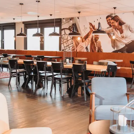 Modern ingerichte kantoorruimte met lange tafels en zitmogelijkheden in kantoorpand aan de Vlamoven 34, Arnhem IJsseloord. Ideaal om te gebruiken voor vergaderingen of informeel overleg.