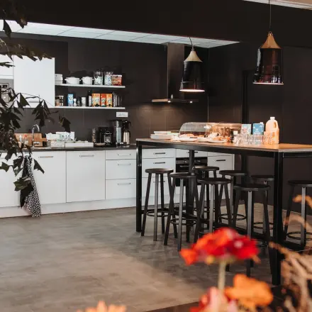 Moderne pantry in een kantoorpand op Vlamoven 34, Arnhem IJsseloord. Ruimte met strak design, voorzien van een hoog tafelblad en krukken, ideaal voor kantoorruimte huren.