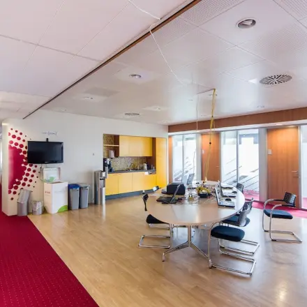 Kantoorruimte huren in Arnhem Zuid met moderne vergadertafel, stoelen, tv-scherm en koffiehoek op Kronenburgsingel 525.