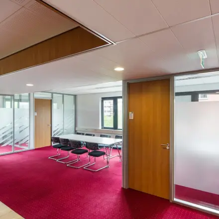 Kantoorruimte huren in Arnhem Zuid: moderne werkruimte met rode vloerbedekking, glazen wanden en vergaderruimte gelegen op Kronenburgsingel 525. Deze kantoorruimte biedt een professionele omgeving voor zakelijke activiteiten.