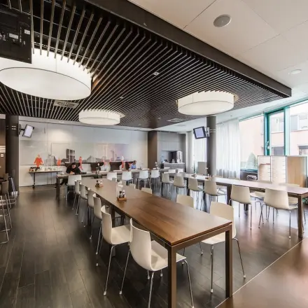 Moderne kantoorruimte in Arnhem Zuid met ruime tafels en stijlvolle verlichting, bij Kronenburgsingel 525. Mensen zijn druk aan het werk in een open en lichte omgeving.