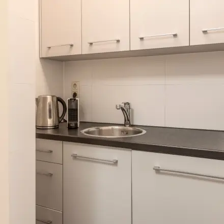 Functionele pantry in een Barendrechts kantoorpand met witte kasten en een donker aanrechtblad, ideaal voor een snelle break tijdens het kantoorwerk.