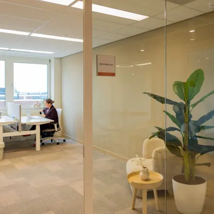 Heldere kantoorruimte op Baron van Nagellstraat 136, Barneveld, met moderne werkplekken en uitzicht. Twee mensen zijn aan het werk.