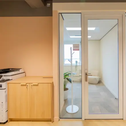 Kantoorruimte huren in Barneveld aan Baron van Nagellstraat 136, met een moderne kantoorpand-interieur, een printer en een glazen deur die naar een lichte werkplek leidt.