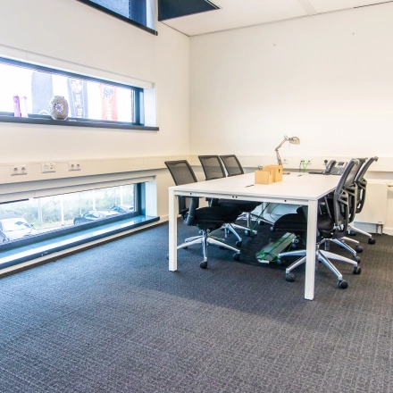 Lichte kantoorruimte te huur op Ceresstraat 1 in Breda Centrum-Station met grote ramen, moderne bureaus en stoelen, geschikt voor zakelijke activiteiten.