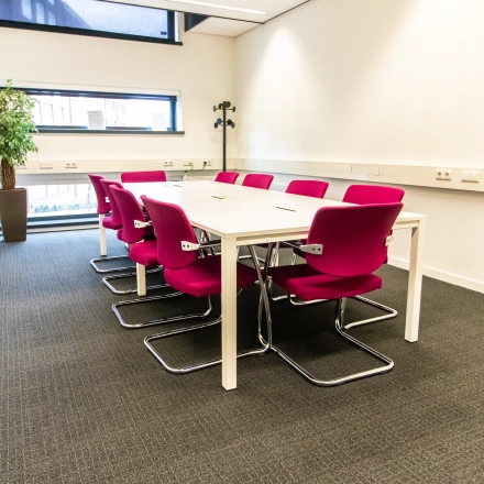 Vergaderruimte met roze stoelen rond een tafel in een kantoor op Ceresstraat 1, Breda Centrum-Station, geschikt voor kantoorruimte huren.
