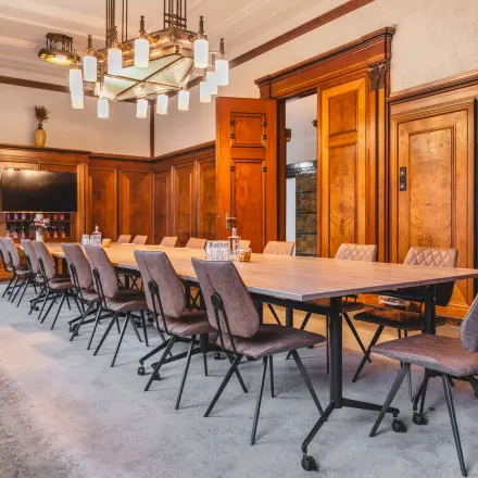 Ruime vergaderruimte in een kantoorpand op Ceresstraat 13, Breda Centrum-Station, met houten panelen, lange tafel en moderne stoelen.