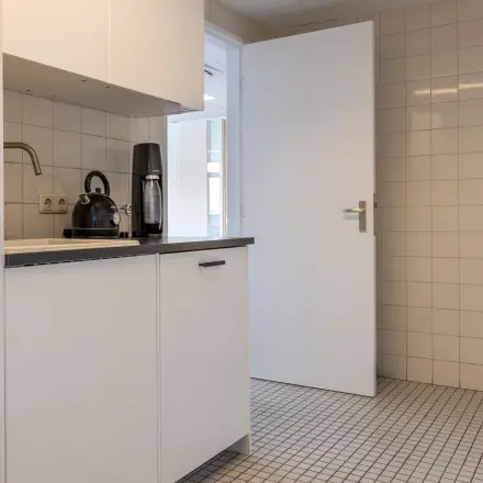 Kantoorruimte te huur aan de Druivenstraat 25-31 in Breda Oost, met een compacte kitchenette voorzien van een koffiezetapparaat en tegelwanden, ideaal voor kantoorgebruik.