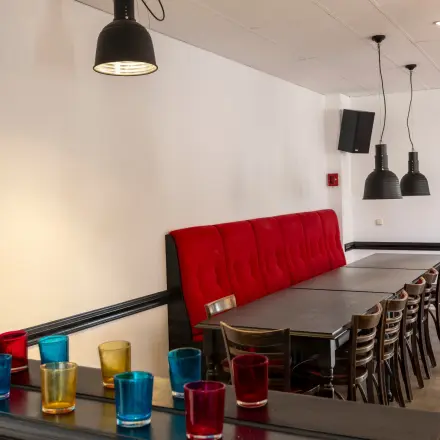 Herkenbare kantoorpand ambiance in Breda Oost aan Druivenstraat 25-31 met een strak ingerichte ruimte voorzien van een lange tafel en kleurrijke glazen op een kast.