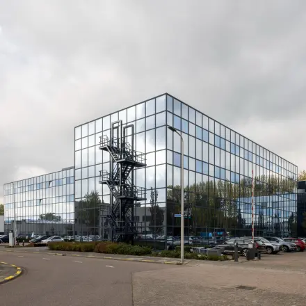 Modern kantoorpand met spiegelende gevel aan de Essebaan 63 in Capelle aan den IJssel, met parkeergelegenheid op de voorgrond.