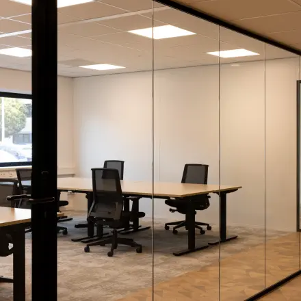 Kantoorruimte met glazen wanden, voorzien van bureaus en stoelen, gelegen op Essebaan 63 in Capelle aan den IJssel. Deze stijlvolle kantooromgeving is klaar voor verhuur.