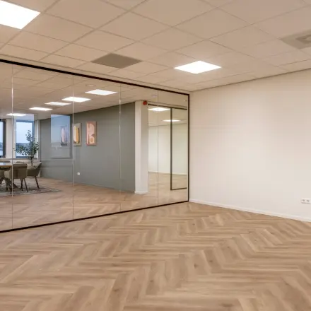 Moderne kantoorruimte aan de Vlierbaan 20, Capelle aan den IJssel, met houten vloer en glazen wand. Ideaal voor bedrijven om kantoor te huren. Grote ramen zorgen voor veel natuurlijk licht.