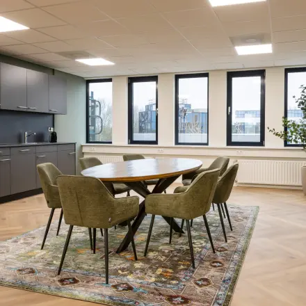 Moderne kantoorruimte met ronde tafel en zes stoelen, vlakbij het raam, op Vlierbaan 20. Voorzien van een kitchenette. Ideaal voor wie kantoorruimte wil huren in Capelle aan den IJssel.
