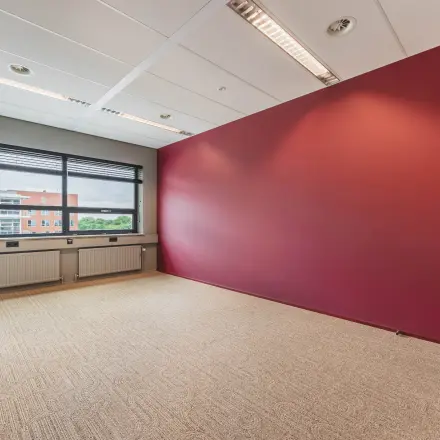 Kantoorruimte te huur in De Meern op Rijnzathe 12, met rood accentmuur en groot raam dat zorgt voor veel lichtinval. Perfecte ruimte om een eigen kantoor te creëren.