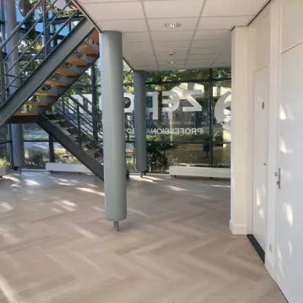 Een lichte entree van het kantoorpand aan Delftechpark 17-19 in Delft met grote ramen en een trap. Ideaal voor kantoorruimte huren met een moderne uitstraling.