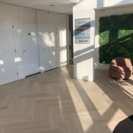 Ingang van het kantoorpand op Delftechpark 17-19 in Delft met een groene plantenwand en een comfortabele zitstoel, ideaal voor als je kantoorruimte wilt huren.