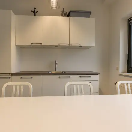 Moderne kantoorruimte in Delft met strakke keukenfaciliteiten en neutrale tinten, ideaal voor ontspanning of informele bijeenkomsten tijdens een drukke werkdag.