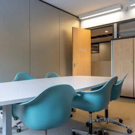 Vergaderruimte in kantoorpand op Delftechpark 9, Delft met lange tafel, blauwe stoelen en een kast. Perfect voor kantoorruimte huren die inspirerend en functioneel is.